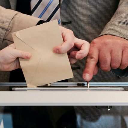Quelqu'un met une enveloppe dans une urne de vote